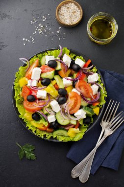 Yunan salatası siyah beton zemin üzerine seramik plaka. Geleneksel Yunan yemeği. Seçici odak. Üstten Görünüm.