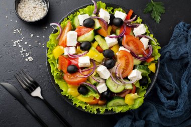 Yunan salatası siyah beton zemin üzerine seramik plaka. Geleneksel Yunan yemeği. Seçici odak. Üstten Görünüm.