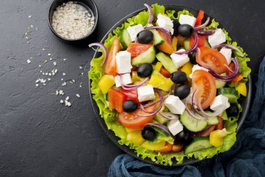 Yunan salatası siyah beton zemin üzerine seramik plaka. Geleneksel Yunan yemeği. Seçici odak. Üstten Görünüm.