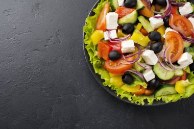 Yunan salatası siyah beton zemin üzerine seramik plaka. Geleneksel Yunan yemeği. Seçici odak. Üstten Görünüm.