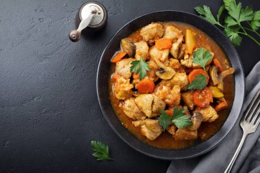 Gulaş geleneksel Macar yemeği. Koyu siyah taş veya beton arka plan üzerinde seramik tabak içinde biber ve domates soslu güveç. Seçici odak. Üstten Görünüm.