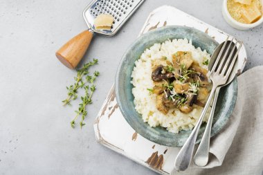 Risotto ile tavuk ve mantar, kekik, sarımsak, eski gri beton zemin üzerine parmesan peyniri. Geleneksel İtalyan yemeği. Seçici odak. Rustik tarzı. Üstten Görünüm.