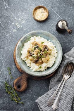 Risotto ile tavuk ve mantar, kekik, sarımsak, eski gri beton zemin üzerine parmesan peyniri. Geleneksel İtalyan yemeği. Seçici odak. Rustik tarzı. Üstten Görünüm.