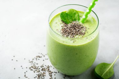 Avokado, ıspanak yaprakları, apple ve chia tohum gri beton zemin üzerine vejetaryen sağlıklı yeşil smoothie. Seçici odak. Metin için yer.