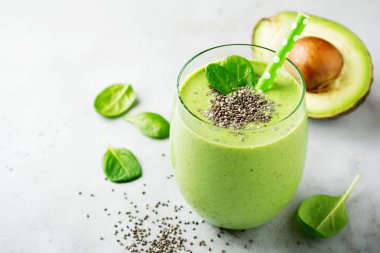 Avokado, ıspanak yaprakları, apple ve chia tohum gri beton zemin üzerine vejetaryen sağlıklı yeşil smoothie. Seçici odak. Metin için yer.