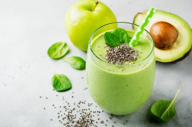 Avokado, ıspanak yaprakları, apple ve chia tohum gri beton zemin üzerine vejetaryen sağlıklı yeşil smoothie. Seçici odak. Metin için yer.