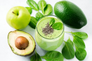 Avokado, ıspanak yaprakları, apple ve chia tohum gri beton zemin üzerine vejetaryen sağlıklı yeşil smoothie. Seçici odak. Metin için yer.