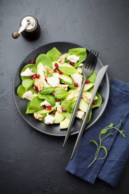 Taze yararlı vejetaryen sağlıklı avokado, ıspanak, nar taneleri, ceviz, safran, biber ve ricotta Salata siyah arka plan üzerine. Seçici odak. Üstten Görünüm. Metin için yer kopyalayın.