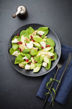Taze yararlı vejetaryen sağlıklı avokado, ıspanak, nar taneleri, ceviz, safran, biber ve ricotta Salata siyah arka plan üzerine. Seçici odak. Üstten Görünüm. Metin için yer kopyalayın.