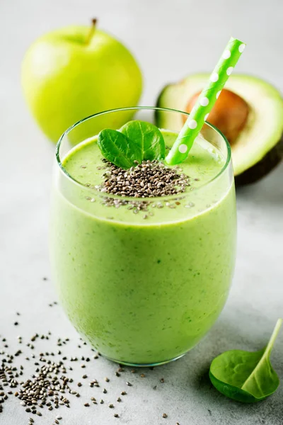 Vegetarian healthy green smoothie from avocado, spinach leaves, apple and chia seeds on gray concrete background. Selective focus. Space for text.