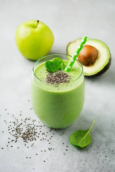 Vegetarian healthy green smoothie from avocado, spinach leaves, apple and chia seeds on gray concrete background. Selective focus. Space for text.