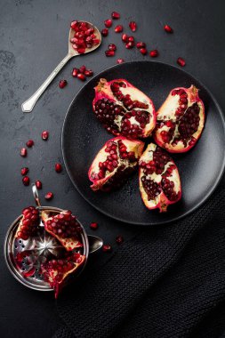 Taze olgun nar, siyah beton veya taş arka plan üzerinde parçalar halinde kesilmiş. Seçici odak. Metin için yer. Üstten Görünüm.