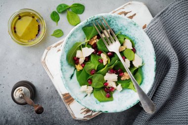 Taze yararlı vejetaryen sağlıklı ıspanak, nar taneleri, ceviz, safran, biber ve ricotta Salata gri arka plan üzerinde. Seçici odak. Üstten Görünüm. Metin için yer kopyalayın.