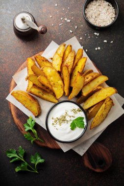 Otlar ve koyu kahverengi beton veya seramik zemin ahşap stand sosu Fırında patates. Seçici odak. Yukarıdan görüntüleyin. Metin için yer.