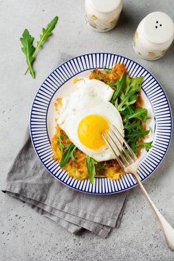 Patates tava keki, roka ve avokado seramik plaka gri eski beton zemin üzerine kahvaltıda sahanda yumurta. Seçici odak. Üstten Görünüm. Kopya alanı.