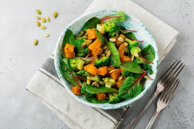 Fırında kabak, pazı, brokoli ve kabak çekirdeği seramik plaka taş veya beton arka plan tablo arka plan salatası. Seçici odak. Rustik tarzı. Üstten Görünüm. Kopya alanı.