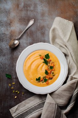 Eski bir taş veya beton zemin üzerine beyaz seramik tabak içinde ev yapımı balkabağı çorbası. Seçici odak. Üstten Görünüm. Kopya alanı.