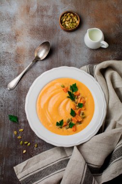 Eski bir taş veya beton zemin üzerine beyaz seramik tabak içinde ev yapımı balkabağı çorbası. Seçici odak. Üstten Görünüm. Kopya alanı.