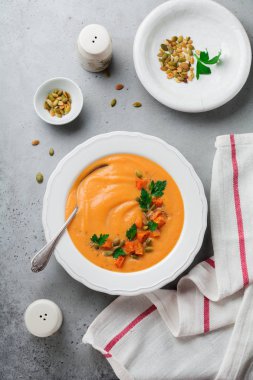 Eski gri beton veya taş zemin üzerine beyaz seramik tabak içinde ev yapımı balkabağı çorbası. Seçici odak. Üstten Görünüm. Kopya alanı.