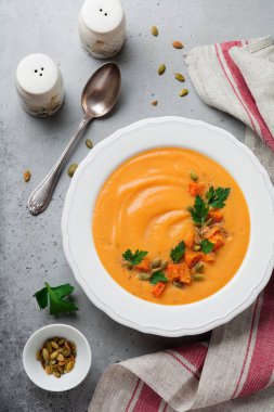 Eski gri beton veya taş zemin üzerine beyaz seramik tabak içinde ev yapımı balkabağı çorbası. Seçici odak. Üstten Görünüm. Kopya alanı.