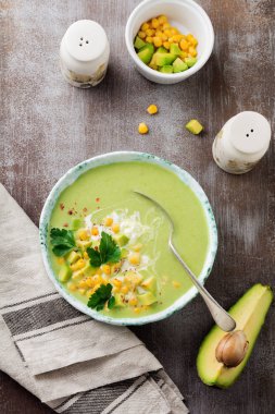 Ev yapımı ihale çorba püresi avokado ve rustik seramik plaka gri beton eski arka plan üzerinde kremalı mısır. Seçici odak. Üstten Görünüm. Kopya alanı.