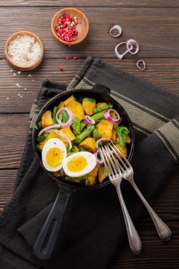 Sıcak patates salatası yeşil fasulye, biber, maydanoz, yumurta ve tavada eski ahşap arka plan üzerinde kırmızı soğan ile. Seçici odak. Üstten Görünüm. Kopya alanı.