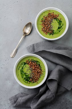 Yararlı smoothies buğday gevreği gri beton tablo arka plan üzerinde seramik kase ıspanak üzerinden. Seçici odak. Üstten Görünüm. Kopya alanı.