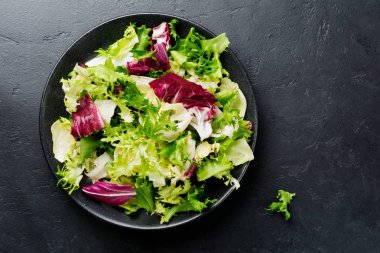 Siyah taş zemin üzerine taze yaprakları seramik plaka farklı salata. Seçici odak. Üstten Görünüm. Kopya alanı.