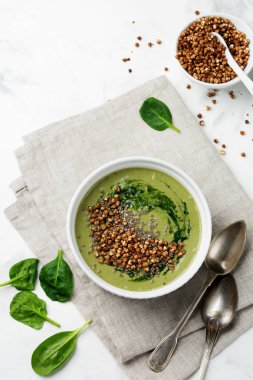 Yararlı smoothies buğday gevreği gri beton tablo arka plan üzerinde seramik kase ıspanak üzerinden. Seçici odak. Üstten Görünüm. Kopya alanı.