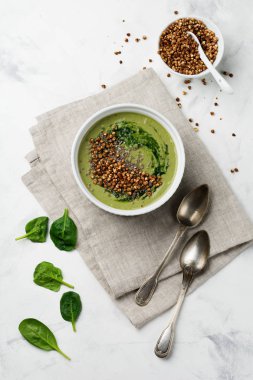 Yararlı smoothies buğday gevreği gri beton tablo arka plan üzerinde seramik kase ıspanak üzerinden. Seçici odak. Üstten Görünüm. Kopya alanı.