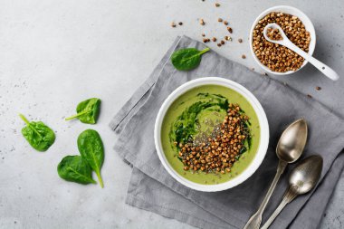 Yararlı smoothies buğday gevreği gri beton tablo arka plan üzerinde seramik kase ıspanak üzerinden. Seçici odak. Üstten Görünüm. Kopya alanı.