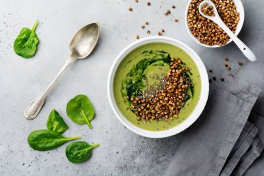 Yararlı smoothies buğday gevreği gri beton tablo arka plan üzerinde seramik kase ıspanak üzerinden. Seçici odak. Üstten Görünüm. Kopya alanı.