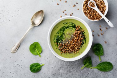 Yararlı smoothies buğday gevreği gri beton tablo arka plan üzerinde seramik kase ıspanak üzerinden. Seçici odak. Üstten Görünüm. Kopya alanı.