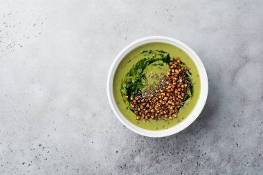 Yararlı smoothies buğday gevreği gri beton tablo arka plan üzerinde seramik kase ıspanak üzerinden. Seçici odak. Üstten Görünüm. Kopya alanı.