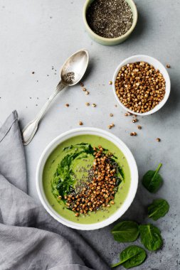 Yararlı smoothies buğday gevreği gri beton tablo arka plan üzerinde seramik kase ıspanak üzerinden. Seçici odak. Üstten Görünüm. Kopya alanı.