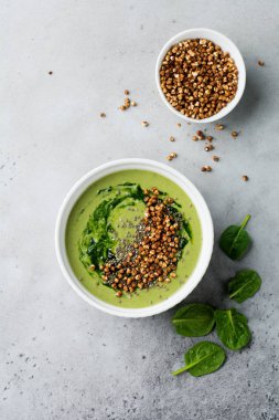 Yararlı smoothies buğday gevreği gri beton tablo arka plan üzerinde seramik kase ıspanak üzerinden. Seçici odak. Üstten Görünüm. Kopya alanı.