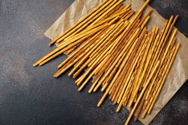 Tuzlu ekmek sopa veya uzun gevrek tuzlu kraker parşömen kağıt üzerine eski kahverengi taş veya beton arka plan üzerinde sopa. Seçici odak. Üstten Görünüm.