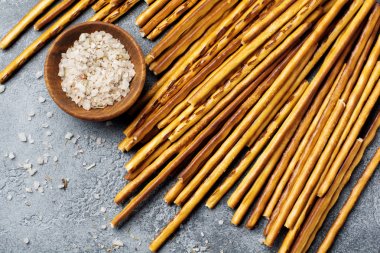 Tuzlu ekmek sopa veya uzun gevrek tuzlu kraker parşömen kağıt üzerine eski gri taş veya beton arka plan üzerinde sopa. Seçici odak. Üstten Görünüm.