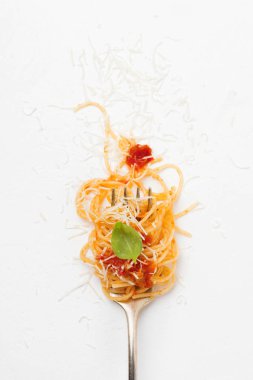 Spagetti çatalı, açık renkli domates sosu ve fesleğen yaprağı. Seçici odak. Üstten Görünüm.