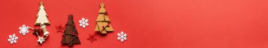 Tahta Noel ağacı oyuncaklarından, kar tanelerinden ve kırmızı arka plandaki yıldızlardan oluşan Noel deseni. Düz yerde, üst tarafta. Yeni yıl konsepti. Üst manzara, minimal noel tarzı ve tatil konsepti. Site için pankart.