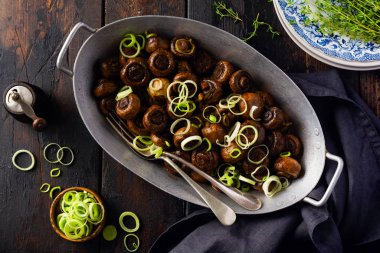 Soya sosunda kızartılmış mantar şampiyonu, biberli ve eski bir masada eski bir metal kasede buğulanmış soğan. Üst görünüm. 