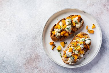 Fırınlanmış balkabağı sandviçi, mavi küflü Dorblu peynirli, bal ve kekik, beton, eski, aydınlık arka planda. Üst görünüm.