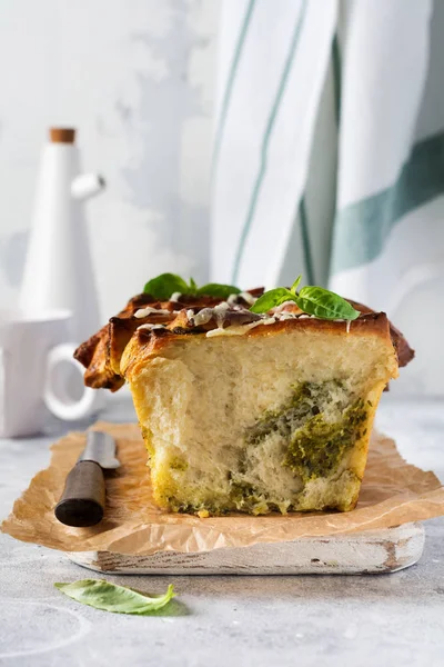 Pull-apart bread with Italian pasta pesto, basil and parmesan cheese in baking form over old light concrete background. Top view. Rustic stile.
