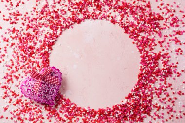 Pembe ışıklı arka planda hediye kalbi olan küçük kalplerden oluşan süs çerçevesi. Sevgililer Günü masa düzenleme.