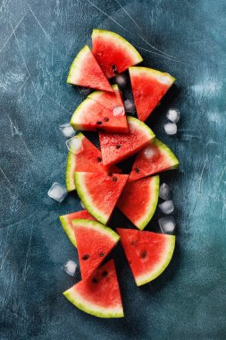 Mavi beton arka planda buzlu taze karpuz dilimleri. Detoks ve vejetaryen konsepti. Üst görünüm, kopyalama alanı, afiş
