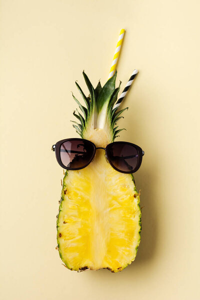 Fresh pineapple cut in two part, notebook or sketchbook and sunglasses on yellow background. Summer concept. Creative flat lay with copy space. Top view.