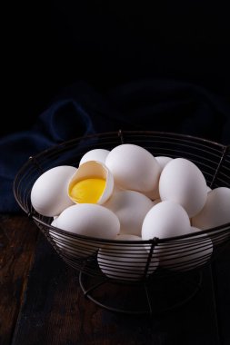 Koyu arkaplanda eski bir sepetin içinde beyaz çiğ tavuk yumurtası.. 