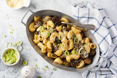 Pipa Rigate ve Mantar Şampiyonu 'nu soya sosunda kızartıp biber, parmesan peyniri ve eski bir masada eski bir metal kasede buğulanmış soğan yapıştırın. Seçici odak. 