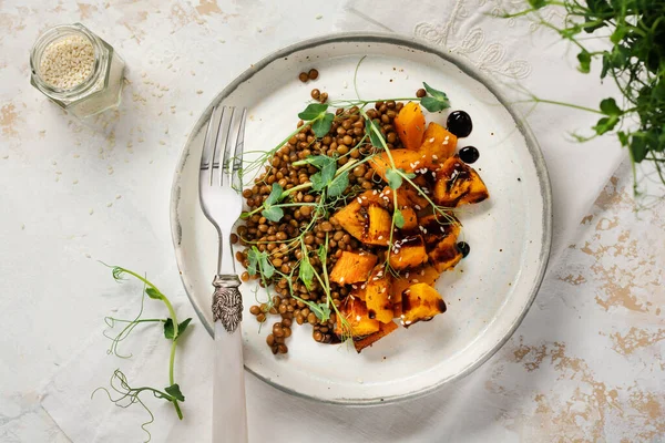 Fırında balkabağı, mercimek ve hafif arkaplanda bezelye mikroçereziyle süslenmiş balzamik soslu salata. Sağlıklı vejetaryen yemekleri..