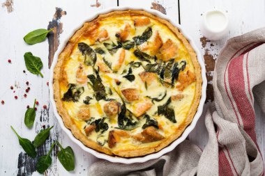 Kırmızı balık ve hafif ahşap zemin üzerine ıspanak ile ev yapımı kiş tart. Vintage tarzı. Üstten Görünüm.